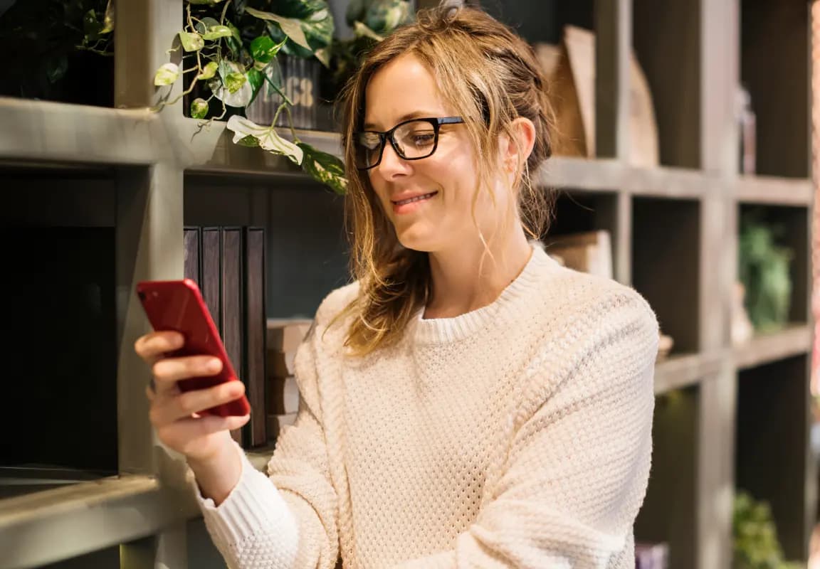 Frau liest ihr Horoskop auf dem Smartphone, Symbol für vertiefte astrologische Beratung und Analyse.