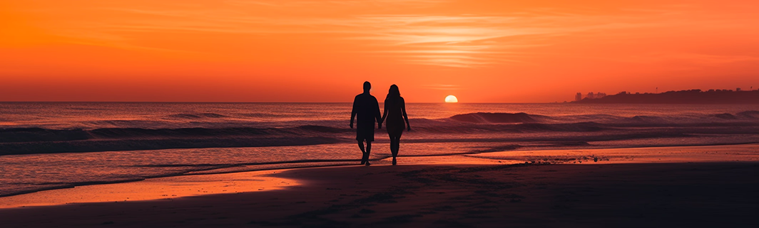 Paar läuft Hand in Hand am Strand bei Sonnenuntergang, Sinnbild für Liebe, tiefe Verbindung und Harmonie in Beziehungen