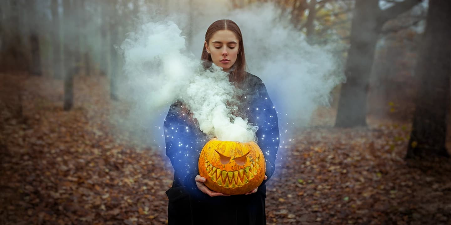 Junge Frau hält einen geschnitzten Kürbis mit magischem Rauch – Symbol für Halloween, Samhain und die spirituelle Bedeutung des 31. Oktober als Übergang zwischen den Welten.