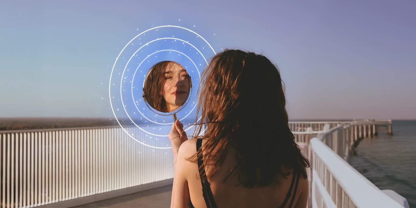 Frau betrachtet ihr Spiegelbild am Meer, symbolische Illustration des Gesetzes der Anziehung und der 5 Schritte zur Manifestation von Träumen.